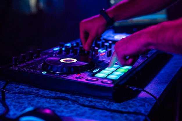 Hands of a DJ playing music on a mixer at a concert