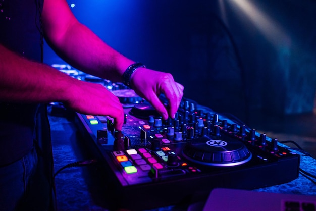 Hands of a DJ playing music on a mixer at a concert