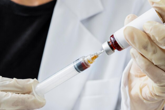 Hands of doctor fill syringe with liquid from a vial