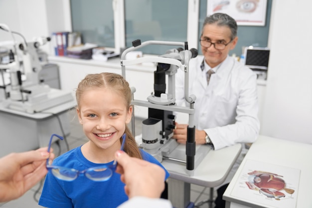 Hands of doctor giving glasses to little patient.