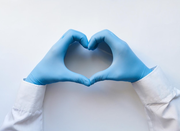 Hands of a doctor or nurse in medical gloves depict a heart on a white background