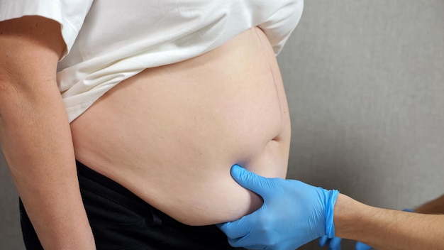 Hands of doctor in rubber gloves examine belly of patient