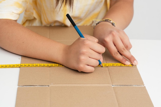 Hands doing crafts marking with a pencil on a cardboard