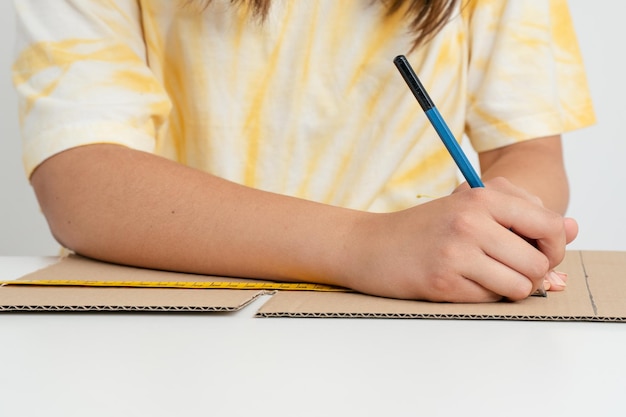 Hands doing crafts marking with a pencil on a cardboard