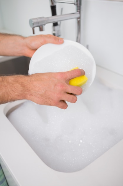 Hands doing the dishes at kitchen sink