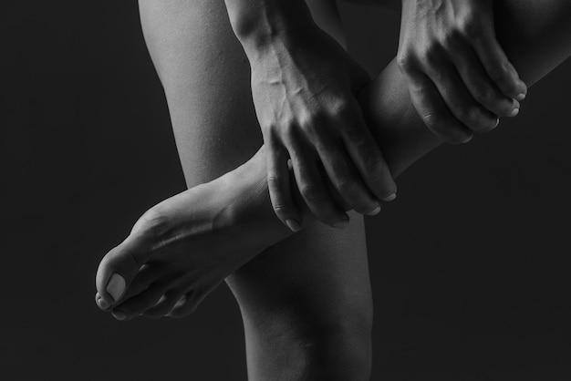 Hands doing leg massage closeup on dark background leg pain concept