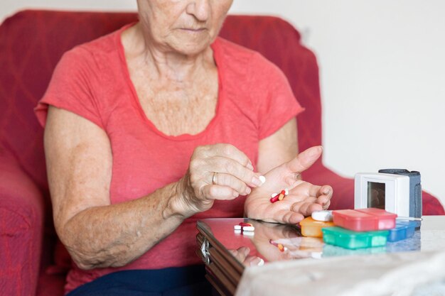 Hands of elderly woman checking her medication medical\
treatment blood pressure monitor at home