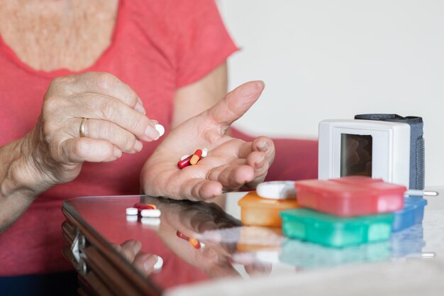 Hands of elderly woman checking her medication medical
treatment blood pressure monitor at home