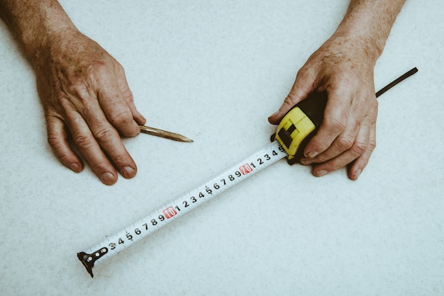 Hands of elderly working man with pencil and roulette close up