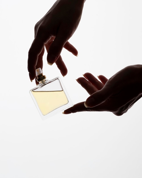 Hands elegantly hold a transparent perfume bottle