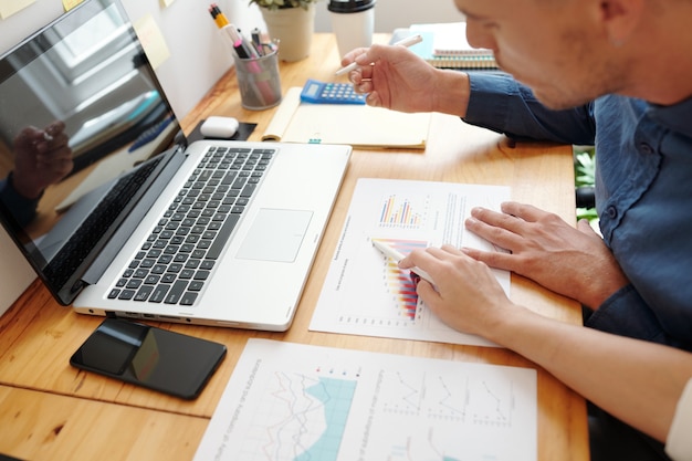 Hands of entrepreneurs having meeting in office to discuss ascending chart in sales data report