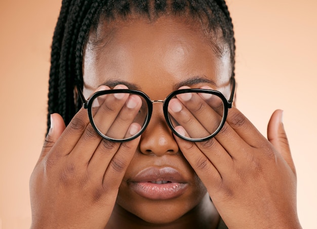 Hands eye health or glasses with a black woman in studio on a beige background covering her face Vision blind and cover with a female indoor to promote eyecare in the optometry or optical industry