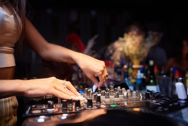 Hands of female dj playing music on modern midi controller turntable digital device for mixing music