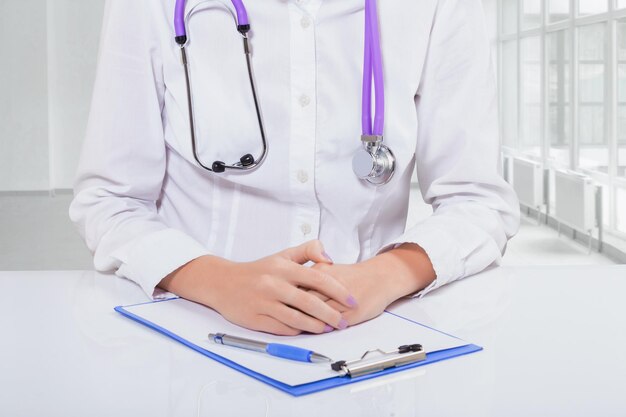 Hands of female doctor on clipboard