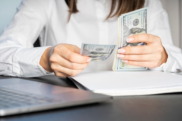 Hands of a financial worker in a white shirt counting money bills. A large bundle of money close-up.