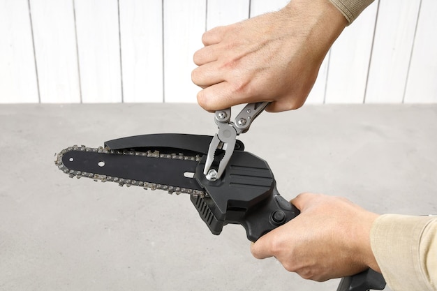 Hands fix nut on portable chain saw with multitool