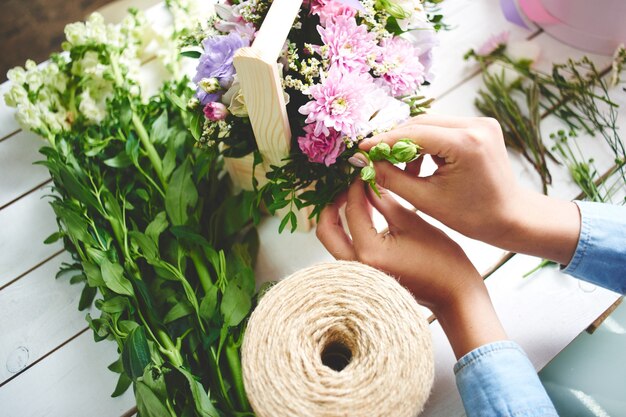 花屋のクローズアップの手がホワイトボードに花束を作ります