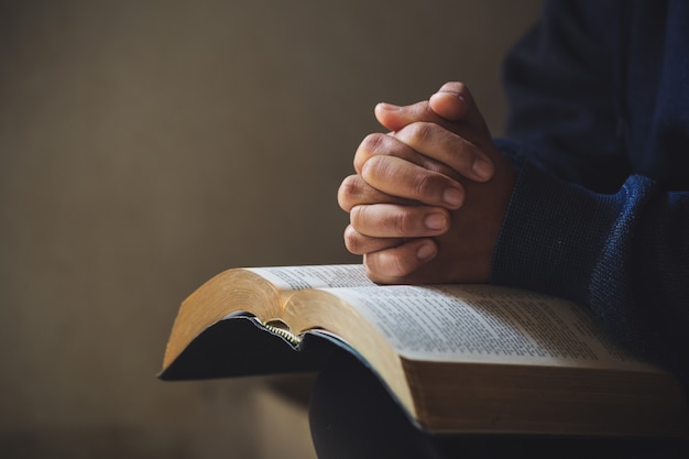 Photo hands folded in prayer on a holy bible in church concept for faith