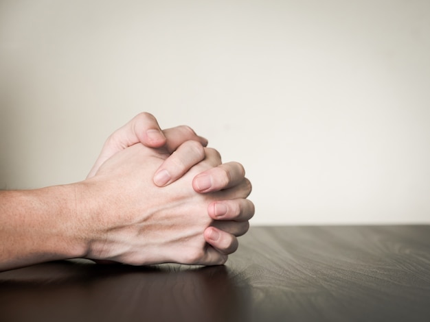 Hands folded together on the table, praying concept