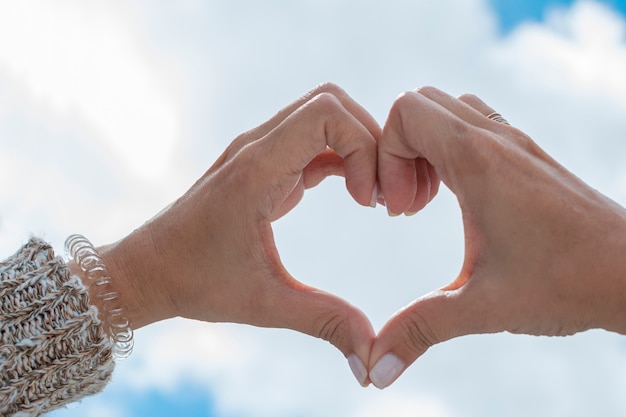 Foto mani che formano un cuore verso il cielo