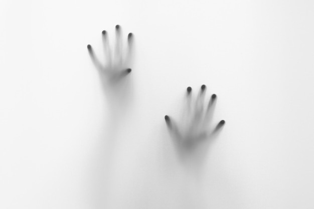 hands behind a frosted glass wall with the word spooky on it