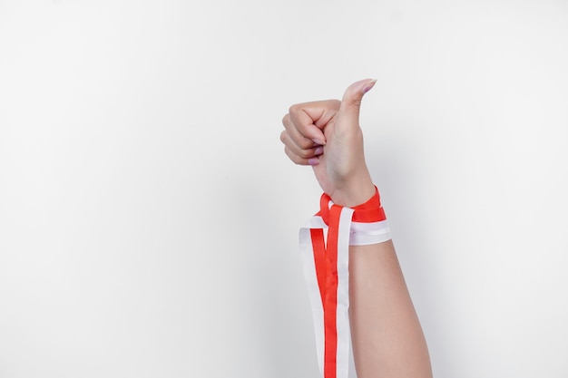 Hands gesturing thumbs up wearing Indonesian red and white ribbon Indonesia39s independence day concept