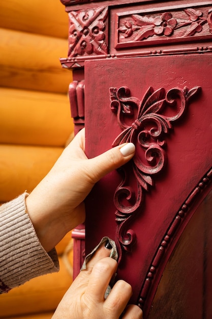 Mani che ottengono cartone colorato di rosso pronto per incollare nuovi adorabili ornamenti intagliati in legno in officina per restauro mobili riutilizzo dare nuova vita a cose vecchie