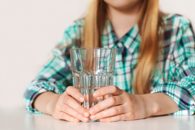 Foto le mani di una ragazza si chiudono, tenendo un bicchiere di acqua pura