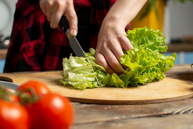 Hands of the girl cut lettuce