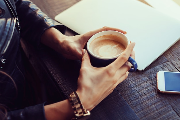 Mani della ragazza che tiene una tazza di caffè