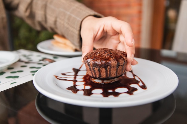 屋外カフェでチョコレートのカップケーキを持ち上げる女の子の手