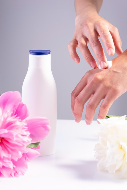 Hands of the girl rubbing cream into the skin on a white floral background Hand skin health skin care hydration