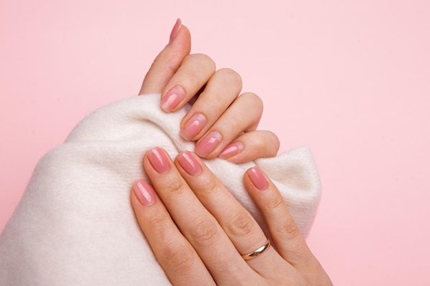 The hands of a girl with nails wellgroomed and untidy and regrown with gel polish and covered with g