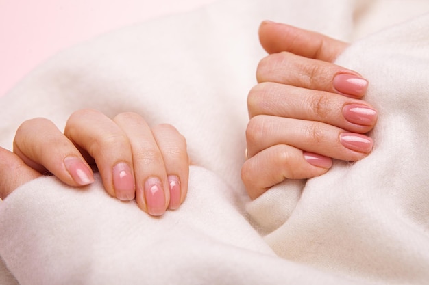 The hands of a girl with nails wellgroomed and untidy and regrown with gel polish and covered with g