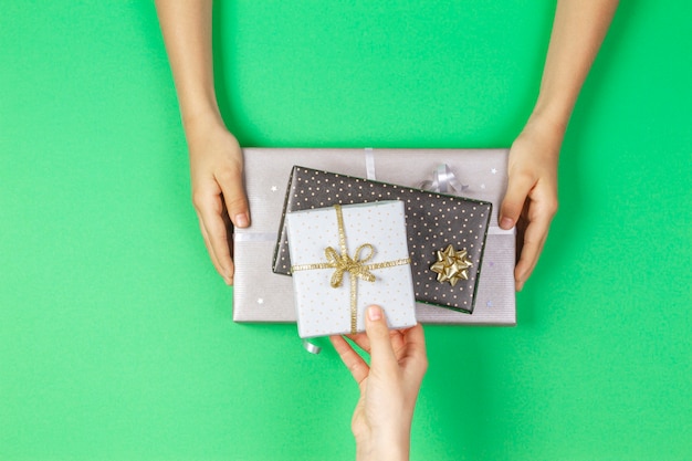 Hands give and take presents boxes over light green background