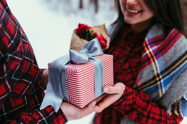 Hands giving a gift box with ribbon. Blurred background. 