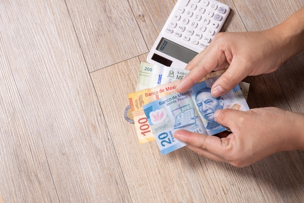 Hands giving money with calculator on wooden table