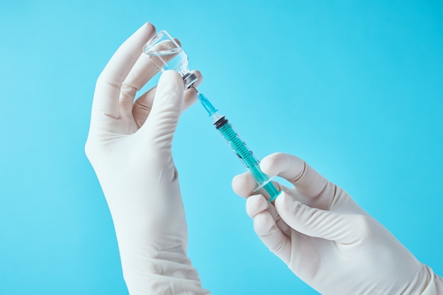 Hands in gloves hold injection syringe and medicine vial ampoule .Healthcare, medical and virus protection concept