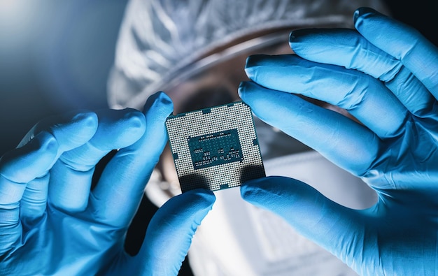 Le mani nei guanti tengono le apparecchiature elettriche dell'elettronica del microprocessore di riparazione del microchip presso una fabbrica di produzione elettronica ultra moderna