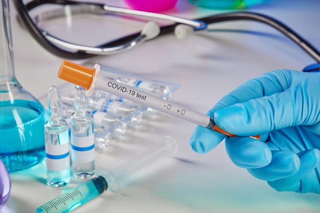hands in gloves holding coronavirus testing kit medical flasks colorful chemical reagents ampoules s