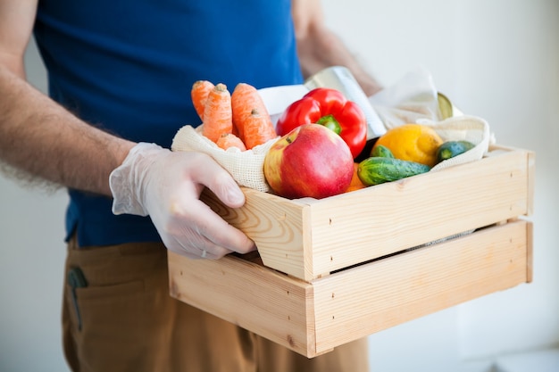 Mani in guanti che tengono la scatola dell'alimento