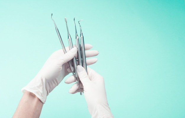 Hands in gloves holding medical tools on light background