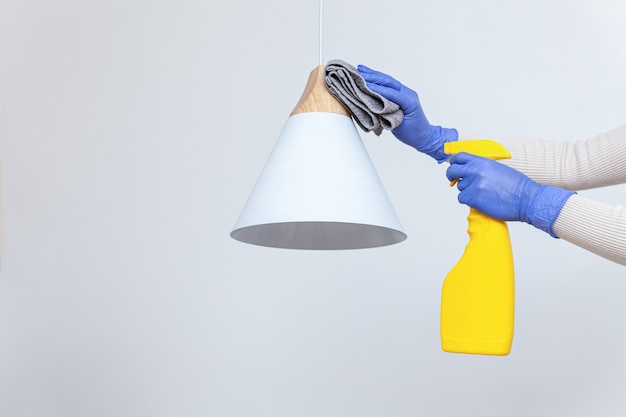 Hands in gloves removing dust cleaning electric lamp chandelier