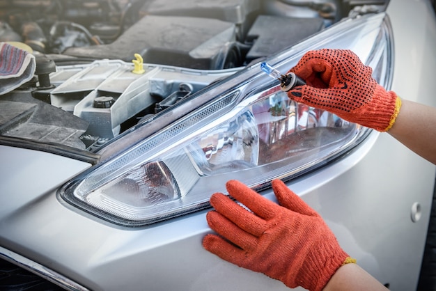 Hands in gloves with lamps near car headlights