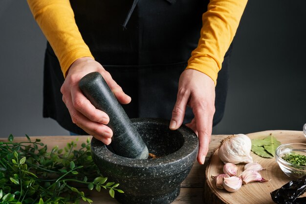 Hands grinding pine nuts in mortar and pestle