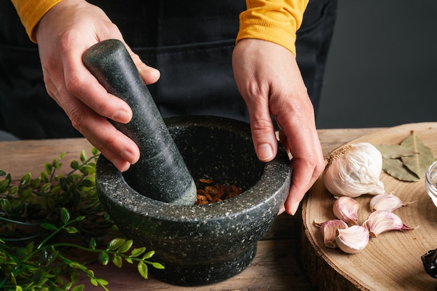 Hands grinding pine nuts in mortar and pestle