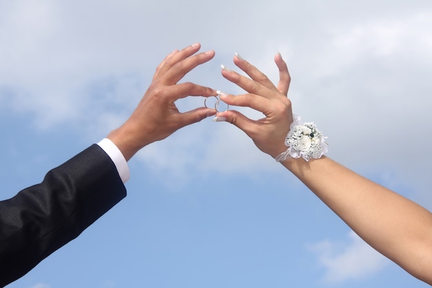 Hands of  groom and  bride hold wedding rings.