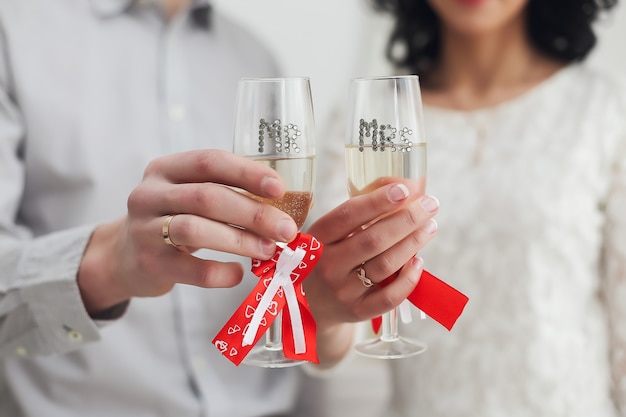 Hands of groom and bride with rings holding glasses with champagne. Wedding, Love, romance, Valentines Day concept. Flat lay, copy space