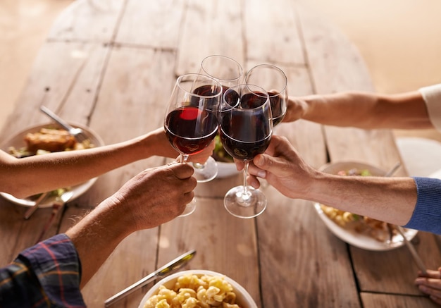 写真 ランチイベントでのお祝いの食べ物や友人のために、テーブルで乾杯するためのグループとワイングラス人々が一緒に集まり、アルコールグラスで祝い、パーティーディナーや家族の家をサポートします
