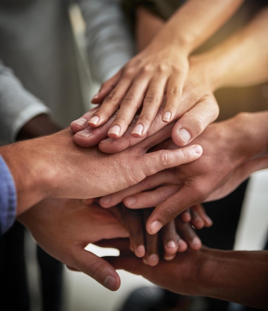 Photo hands of group of corporate business people in unity for motivation success and showing teamwork team of workers employees and colleagues piling hands together for support trust and victory